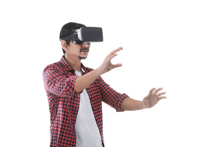 Young asian man experiencing virtual reality through a VR headset isolated on white backgroundの写真素材