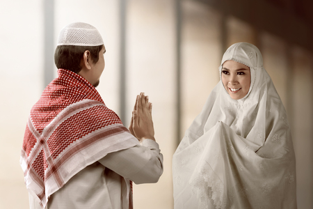 Asian muslim man and woman 
greet each other with muslim tradition with mosque background.の写真素材