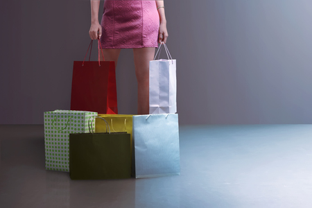 Beautiful young woman standing with shopping bags and boxes in shopping mallの写真素材