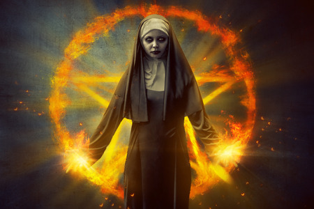 Scary devil nun, with burning pentagram on the backgroundの写真素材