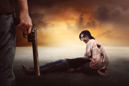 Brave man with jeans pants holding gun looking at zombie eating flesh
