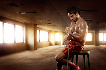 Man asian boxer sitting with wearing white strap on wrist in the gymの写真素材
