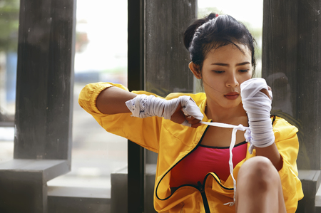 Beauty asian woman in yellow jacket wraps her wrist with white sports wrapの写真素材