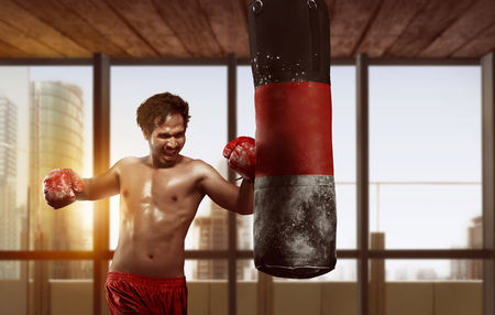 Sporty asian male boxer exercising with punching bag in the skyscraper view backgroundの写真素材