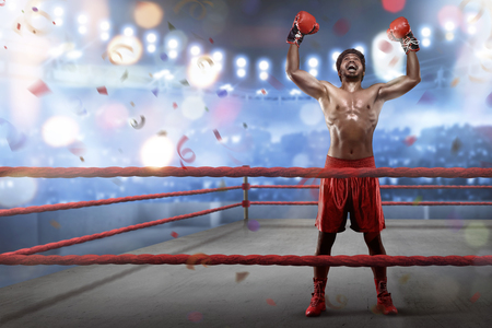 Cheerful asian young boxer is celebrating his winning in the boxing ringの写真素材