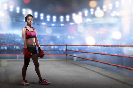 Sexy asian female boxer with boxing gloves standing in the boxing ring at stadiumの写真素材