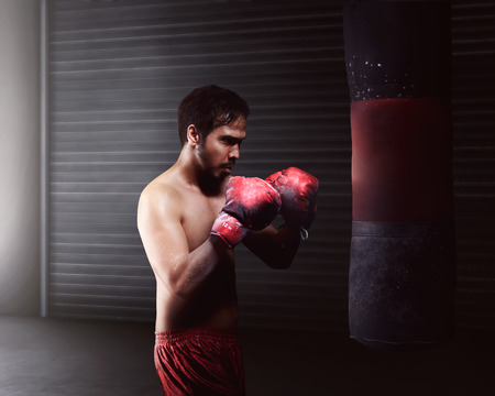 Athletic asian man workout boxing with a heavy punching bagの写真素材