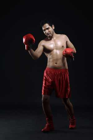 Portrait of asian guy boxer is celebrating his winning over black backgroundの写真素材