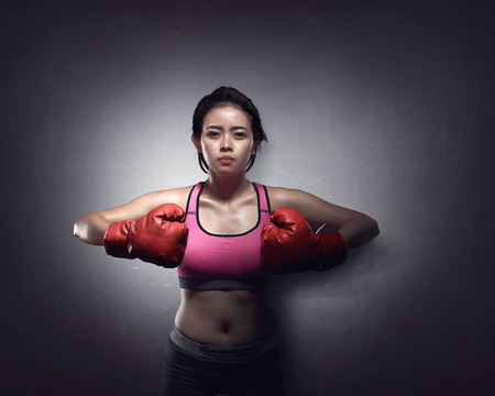 Young asian girl with boxing gloves over black backgroundの写真素材