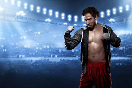 Sporty asian male boxer with white strap in his wrist standing in boxing stadiumの写真素材