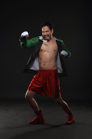 Young asian boxer training boxing against black backgroundの写真素材