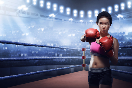 Attractive asian female boxer in boxing arena while trainingの写真素材