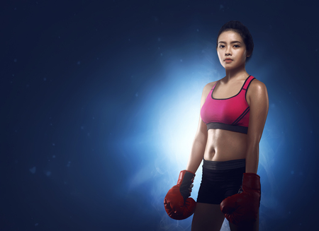 Beautiful asian woman boxer portrait against blue light backgroundの写真素材