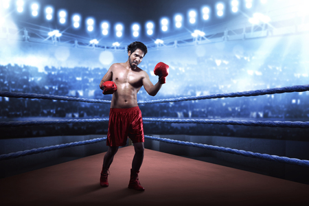 Asian boxer guy training uppercut before the game on the boxing ring arenaの写真素材