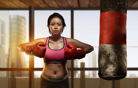 Pretty asian girl boxer doing exercise with punching bag in the modern gymの写真素材