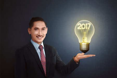 Man showing light bulb with 2017 inside. New year concept idea