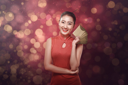 Chinese woman in tradional clothing holding angpao. Happy chinese new year conceptの写真素材
