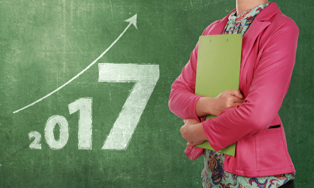 Businesswoman with clipboard standing beside numbers 2017 on the chalkboard