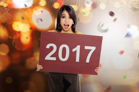 Happy asian woman holding number 2017 on the red board against blurred lightの写真素材