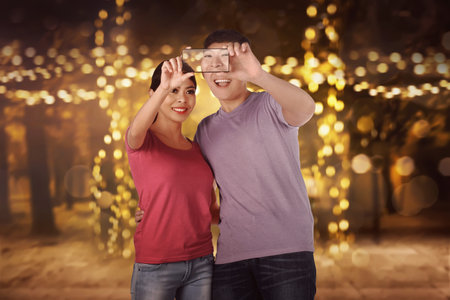 Happy asian couple doing selfie over blurred light background