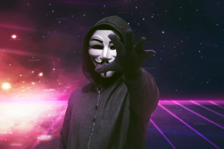 Hooded man with vendetta mask grabbing something over visual backgroundのeditorial素材
