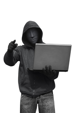 Hooded hacker with mask holding laptop while appoint isolated against white backgroundの写真素材