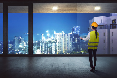 Rear View of asian construction woman looking the construction on the city from the officeの写真素材