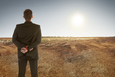 Back view of asian businessman on dry ground and sunset. Climate change conceptの写真素材