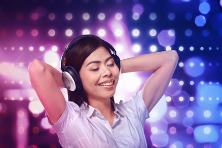 Beautiful asian woman listening music in headphone on blurred light backgroundの写真素材