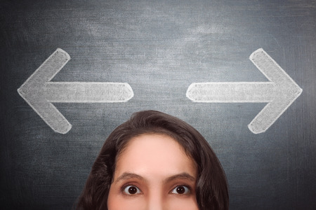 Confusing asian woman with arrow signal on head against black backgroundの写真素材