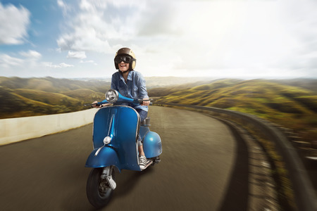 Young asian woman riding motor scooter with helmet along mountain roadの写真素材