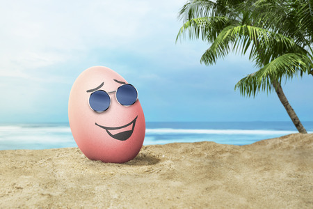 Happy easter eggs with sunglasses in the beach at sunset at dayの写真素材
