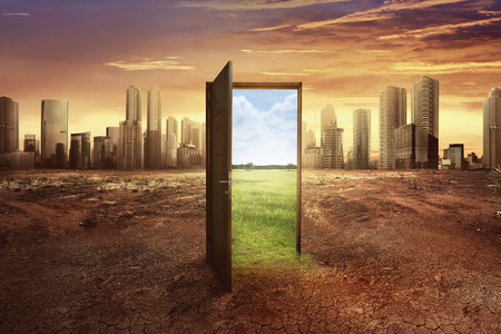 Found new world with green environment from open wooden door against cityscape backgroundの写真素材