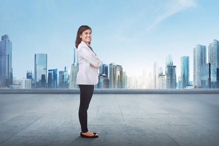 Portrait of a young asian business woman with crossed arm in front of cityscape backgroundの写真素材