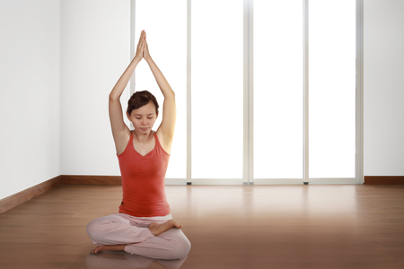 Beautiful asian woman practicing yoga at homeの写真素材
