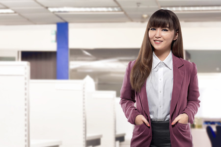 Attractive asian business woman standing in front of desk in an officeの写真素材