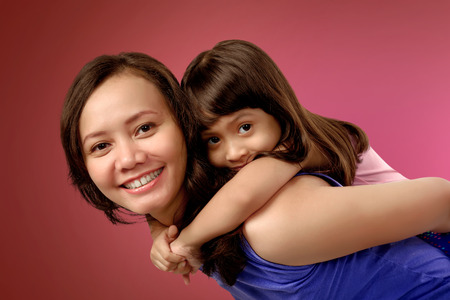 Picture of mother and daughter playing over red background. Mothers day Concept.の写真素材