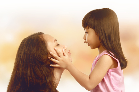 Young mother and her little daughter against light background. Mothers day Concept.の写真素材