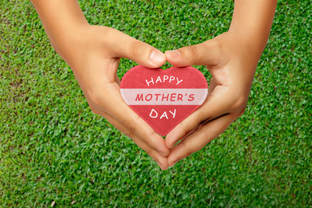 People hand holding heart with Happy Mothers day greeting on grassの写真素材