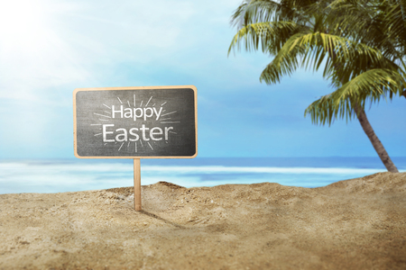 Happy easter greeting on black sign board in the beachの写真素材