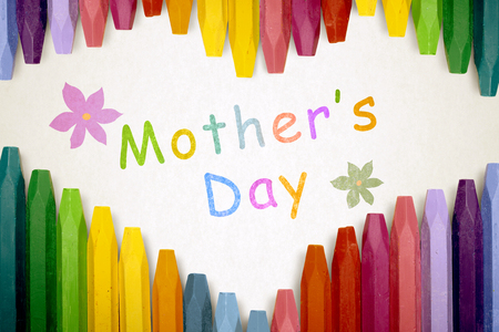 Row of colorful crayon with mothers day message over stripe pattern paperの写真素材