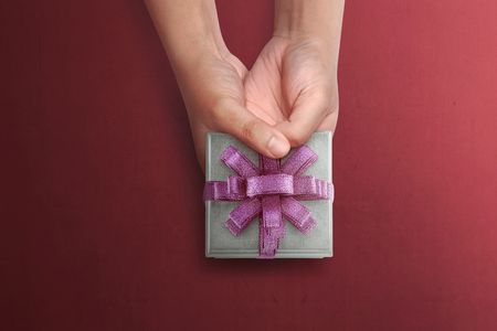 People hand holding small gift for Mother's Day over red backgroundの写真素材