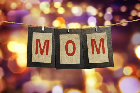 Mom word shape hanging with clothespin over blurred light backgroundの写真素材
