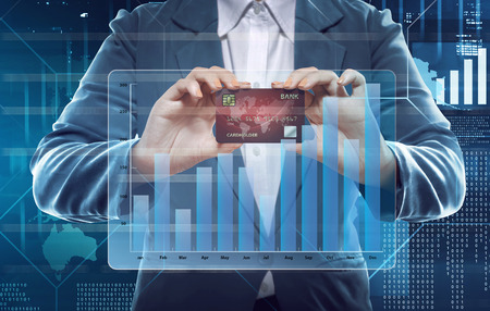 Businesswoman holding new credit card with transparent financial chart against digital backgroundの写真素材