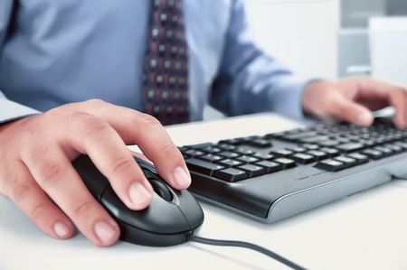 Businessman using computer with hands typing on a keyboard in the officeの写真素材