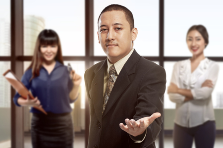 Young businessman standing with open hand ready to hand shake at officeの写真素材