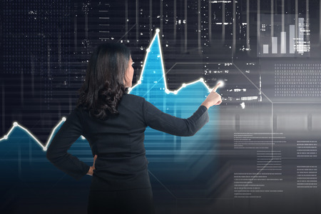 Asian business woman drawing digital graph on virtual screen backgroundの写真素材