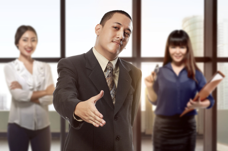 Handsome asian businessman with open hand ready for hand shake in the officeの写真素材