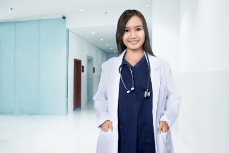 Asian female doctor smiling over hospital backgroundの写真素材