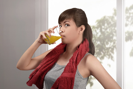 Happy asian woman drink natural orange juice at homeの写真素材
